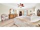 Main bedroom with ceiling fan, sitting area, dresser with mirror, and a large comfortable bed at 5459 Sw 86Th St, Ocala, FL 34476