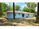 Back exterior view of a light blue home with sliding doors, small patio, and lush green backyard at 6475 Nw 61St Ave, Ocala, FL 34482
