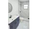 Modern bathroom featuring a dark vanity, round mirror, new tiled shower, and beautiful white tile flooring at 6475 Nw 61St Ave, Ocala, FL 34482