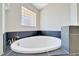 Bathroom soaking tub with dark tile and accenting glass block window at 6631 Se 11Th Loop, Ocala, FL 34472