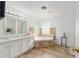 Bathroom featuring double sinks, soaking tub, glass block window, and tile floors at 6730 Sw 9Th Ave, Ocala, FL 34476