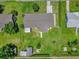 Aerial view of a home with a gray roof, lush lawn, a shed, a patio, and stone walkway at 713 Se 34Th Ter, Ocala, FL 34471