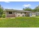 The backyard has a small wooden deck, a blue back door, an air conditioner, and ample green grass at 713 Se 34Th Ter, Ocala, FL 34471