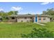 Backyard features a covered patio, lush lawn and landscaping with a blue back door entrance to the residence at 713 Se 34Th Ter, Ocala, FL 34471