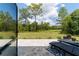 This backyard has a stone patio with black outdoor chairs and a lush green lawn. The large trees give shade on a sunny day at 9746 Sw 108Th Terrace Rd, Ocala, FL 34481