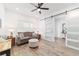 Inviting living area features a ceiling fan, a comfortable couch, and a stylish sliding barn door at 9746 Sw 108Th Terrace Rd, Ocala, FL 34481