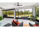 This sunroom features large windows with wooded views, ceiling fans, and comfortable patio furniture for relaxing and enjoying the outdoors at 9746 Sw 108Th Terrace Rd, Ocala, FL 34481