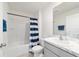 Bright bathroom showcasing a tub, shower, striped curtain, and a modern vanity with a marble countertop at 11205 Se 69Th Ter, Belleview, FL 34420