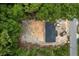 The aerial view showcases the new roof, surrounded by lush trees, with a car and debris container at 11506 Nw 20Th St, Ocala, FL 34482