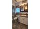 A well-lit bathroom features a vanity with white cabinets, a rustic mirror and a shower with glass doors at 12524 Sw 109Th Pl, Dunnellon, FL 34432