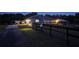 Night view of a quaint home with illuminated features, adjacent buildings, and a fenced perimeter at 12524 Sw 109Th Pl, Dunnellon, FL 34432