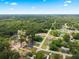 An aerial view of a suburban home surrounded by lush green trees under a clear, blue sky at 13803 Se 44Th Ave, Summerfield, FL 34491