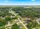 An aerial view of a residential area with tree-lined streets, houses, and expansive greenery under a bright blue sky at 13803 Se 44Th Ave, Summerfield, FL 34491