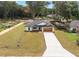 Exterior home view with a large driveway and a two-car garage, surrounded by a well-manicured lawn at 13803 Se 44Th Ave, Summerfield, FL 34491