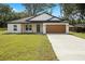 Charming single-story home featuring a well-manicured lawn, attached garage, and welcoming front porch at 13803 Se 44Th Ave, Summerfield, FL 34491