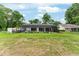 Wide backyard view featuring an enclosed patio, lush grass, and a view of the home's exterior at 19115 Sw 98Th Loop, Dunnellon, FL 34432