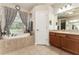 Inviting bathroom with a soaking tub beneath a window and vanity with large mirror at 19115 Sw 98Th Loop, Dunnellon, FL 34432