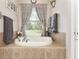 Close-up of a soaking tub beneath a window, complemented by stylish gray towels and décor at 19115 Sw 98Th Loop, Dunnellon, FL 34432