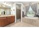 Elegant bathroom showcasing a large vanity, glass shower, and a soaking tub beneath a window at 19115 Sw 98Th Loop, Dunnellon, FL 34432