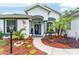 Inviting front entrance with a decorative door, colorful landscaping, and a charming walkway at 19115 Sw 98Th Loop, Dunnellon, FL 34432