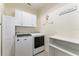 Bright laundry room featuring a washer, dryer, shelving, and storage cabinets at 19115 Sw 98Th Loop, Dunnellon, FL 34432