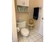 Cozy bathroom featuring a toilet with an overhead cabinet, cream walls, and white tile flooring at 19480 Sw 100Th Loop, Dunnellon, FL 34432