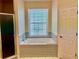 Bathtub with tiled surround next to a window for natural light at 19480 Sw 100Th Loop, Dunnellon, FL 34432