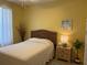 Bedroom featuring a queen bed with a rattan headboard, yellow walls and a white ceiling fan at 19480 Sw 100Th Loop, Dunnellon, FL 34432