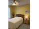 Bedroom featuring a queen bed with a rattan headboard, yellow walls and a white ceiling fan at 19480 Sw 100Th Loop, Dunnellon, FL 34432
