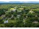 An aerial view captures a verdant neighborhood with a pond, homes, and spacious green properties at 26 Count Fleet Dr, Ocala, FL 34482
