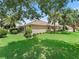 Expansive backyard featuring lush lawn, mature trees, and a screened-in lanai for outdoor enjoyment at 2721 Day Lily Run, The Villages, FL 32162