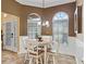 Cozy breakfast nook with a round table, white chairs, and abundant natural light from arched windows at 2721 Day Lily Run, The Villages, FL 32162