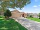 Charming single-story home featuring a well-manicured lawn, mature trees, and a spacious driveway with a decorative medallion at 2721 Day Lily Run, The Villages, FL 32162