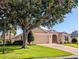 Charming home featuring a well-manicured lawn, a two-car garage, and a lovely front yard tree at 2721 Day Lily Run, The Villages, FL 32162