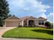 Charming home featuring a well-manicured lawn, a two-car garage, and lovely landscaping at 2721 Day Lily Run, The Villages, FL 32162