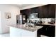 Modern kitchen featuring sleek, dark cabinetry, stainless steel appliances, and an island with granite countertops at 2883 Sw 146Th Place Rd, Ocala, FL 34473