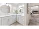 Bright bathroom featuring double sinks, white cabinetry, and a glimpse into an adjoining bedroom at 3001 Hillside Ln, The Villages, FL 32162