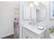 Bathroom vanity featuring octagon mirror, modern faucet, marble counters and view to kitchen at 3001 Hillside Ln, The Villages, FL 32162