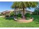 Home with lush, green lawn and tropical landscaping featuring a palm tree in a stone planter at 3001 Hillside Ln, The Villages, FL 32162