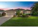 Stunning home exterior featuring lush landscaping, paver driveway and warm exterior lighting at dusk at 3001 Hillside Ln, The Villages, FL 32162