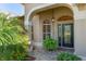 Elegant front entry with arched doorway, decorative glass door, and lush tropical landscaping at 3001 Hillside Ln, The Villages, FL 32162