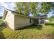 Exterior back view of home featuring a small patio, lawn area, and access to a sunroom through sliding glass doors at 42 Almond Dr, Ocala, FL 34472