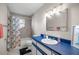 Well-lit bathroom featuring a blue countertop, a shower-tub combo with floral shower curtain, and white tile flooring at 42 Almond Dr, Ocala, FL 34472