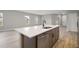 Close-up of a modern kitchen island with a sink, stainless steel dishwasher, and wood cabinets at 5 Larch Course Ter, Ocala, FL 34480