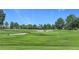 Lush golf course featuring manicured greens, mature trees, and sand traps under a clear blue sky at 5233 Nw 43Rd Lane Rd, Ocala, FL 34482