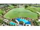 Aerial view of community pools, lush landscaping, and a large pond with a golf course in the background at 5233 Nw 43Rd Lane Rd, Ocala, FL 34482