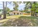 Back exterior view of home featuring a spacious, grassy yard with mature trees at 5596 Nw 57Th St, Ocala, FL 34482