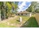 Back exterior view of home featuring a spacious, grassy yard with mature trees and fencing at 5596 Nw 57Th St, Ocala, FL 34482