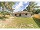 Back exterior view of home featuring a spacious, grassy yard, trees, and fire pit at 5596 Nw 57Th St, Ocala, FL 34482