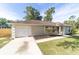 Single-story home featuring an attached garage, classic shutters, adjacent to a long, paved driveway at 5596 Nw 57Th St, Ocala, FL 34482